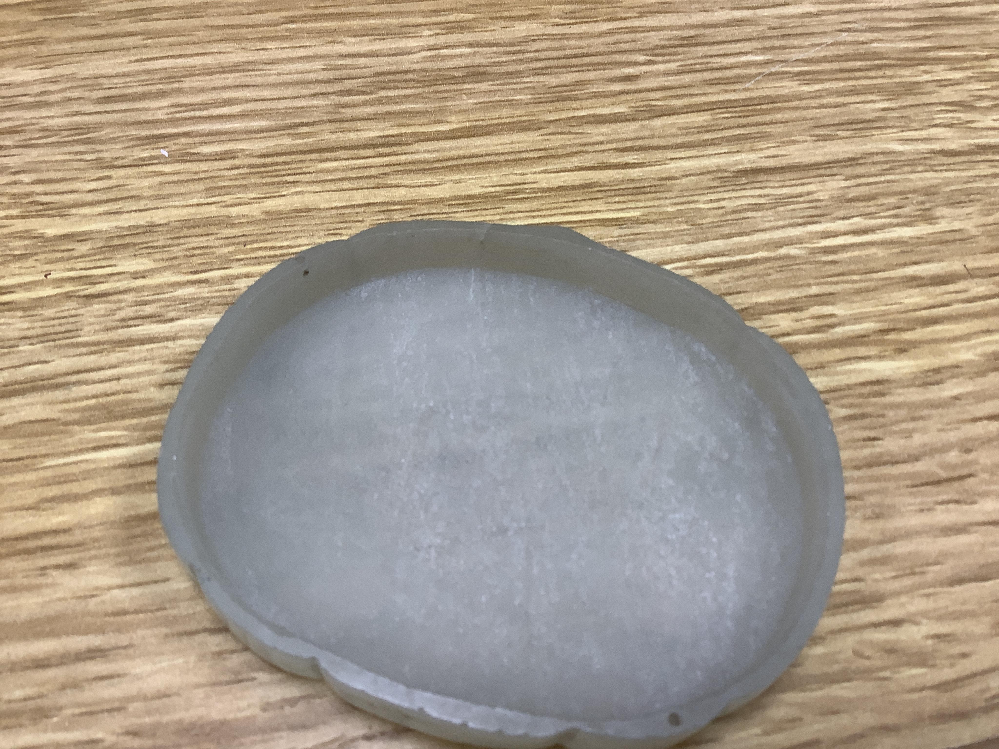 A Chinese pale celadon jade cover for a box, 19th century, carved in relief with a flaming Buddhist wheel emblem, 7.5cm wide. Condition - box base lacking, cover with feint crack